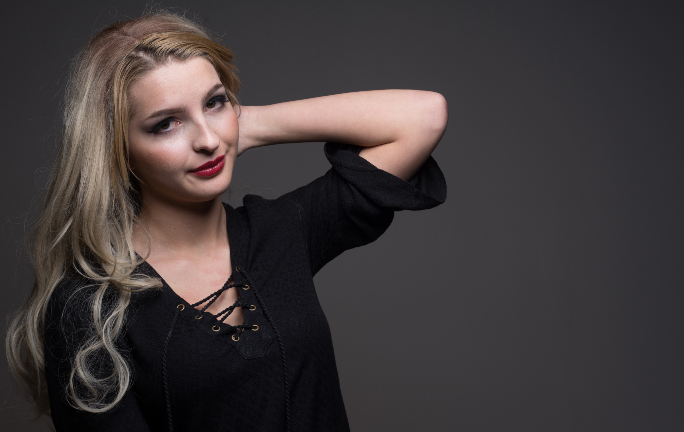 Blond woman looks at the camera with a grey background.